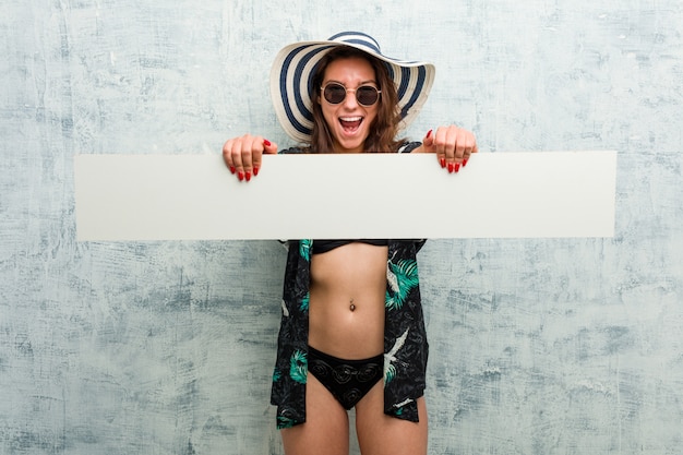 Young european woman wearing bikini and holding a placard