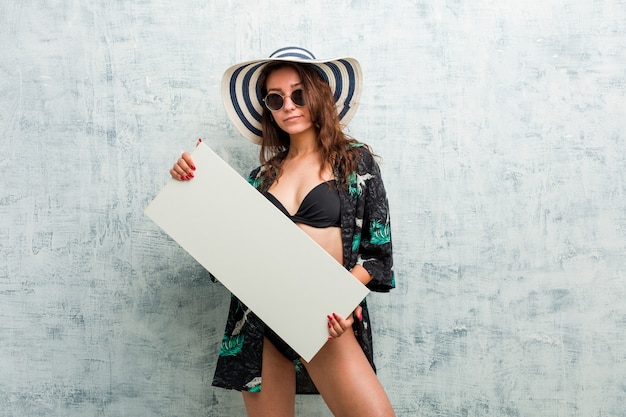 Young european woman wearing bikini and holding a placard