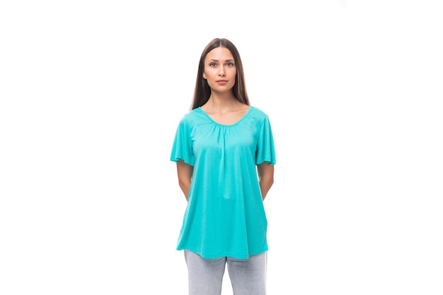 Young european woman with dark long hair dressed in a blue loosefitting tshirt on a white background