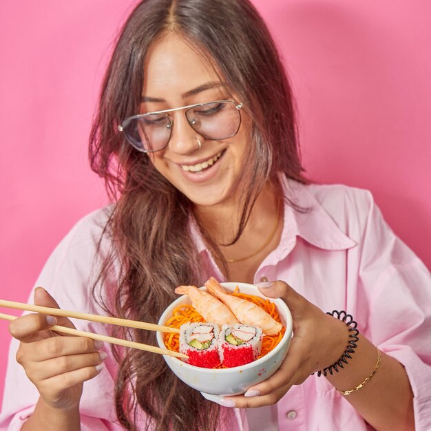 Foto la giovane eccitata e stupita donna fresca e divertente degli anni '20 in abiti casual tiene in mano mangia il rotolo di sushi makizushi