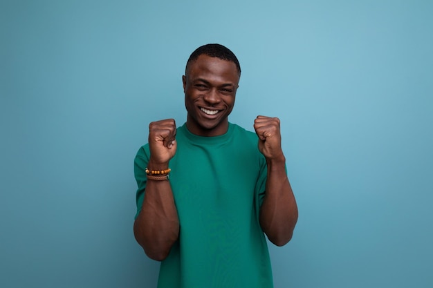 Young excited american man in tshirt on blue background with copy space people lifesal concept