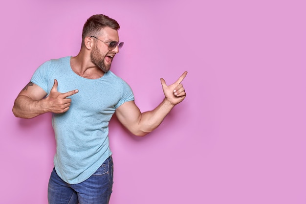 Young excited man on vacation over pink background pointing finger to the side with successful idea