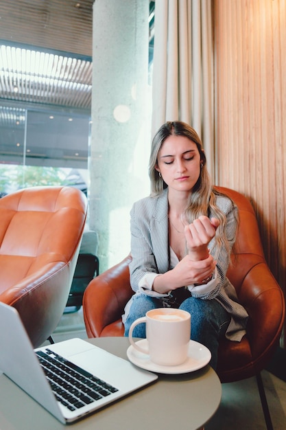 Young executive business woman experiencing pain in her wrist, because of tendonitis.