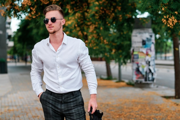 Photo young executive businessman wearing sunglasses while standing outdoors on the street