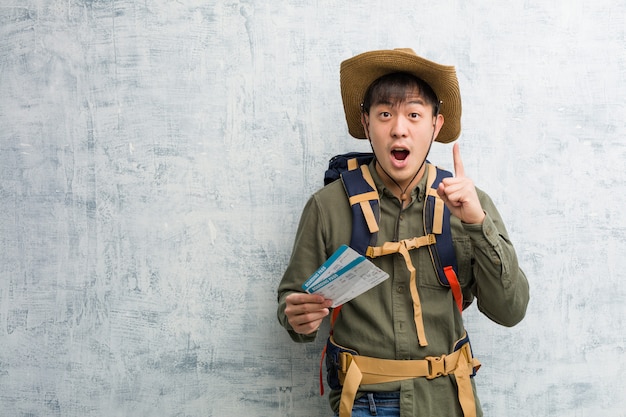 Young explorer chinese man holding an air tickets having a great idea,  of creativity