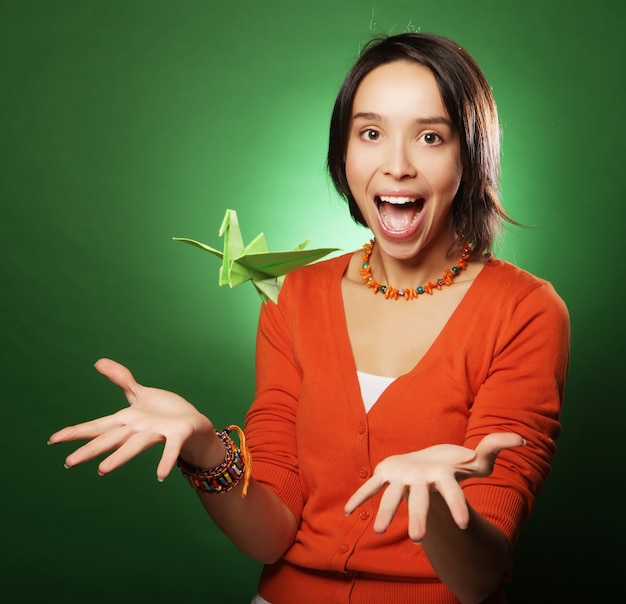 Young expression woman with paper bird over green background