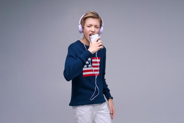 Young expressive singer lover joyful fun caucasian man in casual basic headphones wearing sweater si...