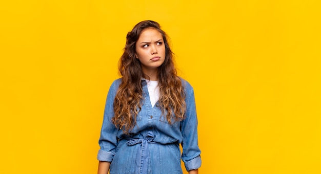 young expressive woman posing on yellow wall