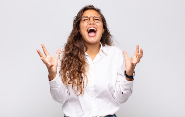 young expressive woman with glasses and elegant white blouse posing on white wall