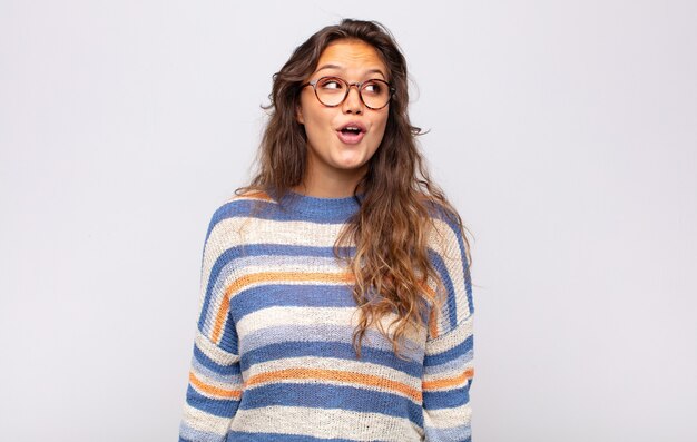 young expressive woman with glasses posing on white wall