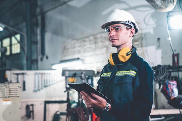 Young factory worker using adept tablet computer in a workshop building