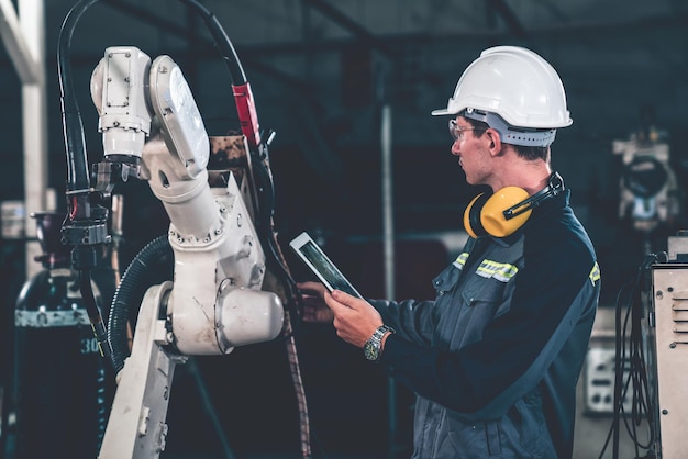 Foto giovane operaio di fabbrica che lavora con un abile braccio robotico