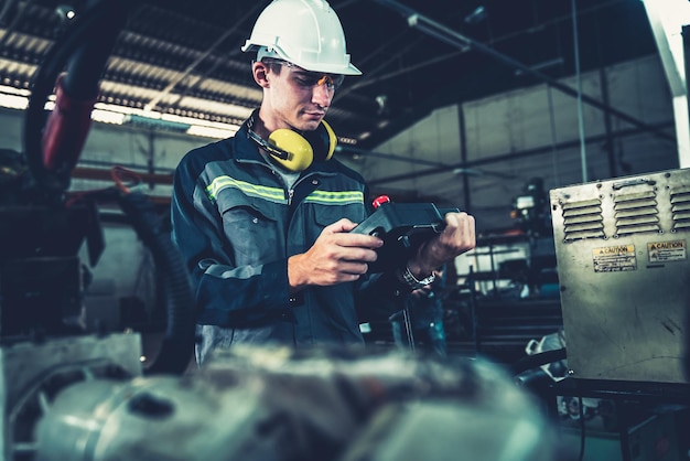 Young factory worker working with adept robotic arm