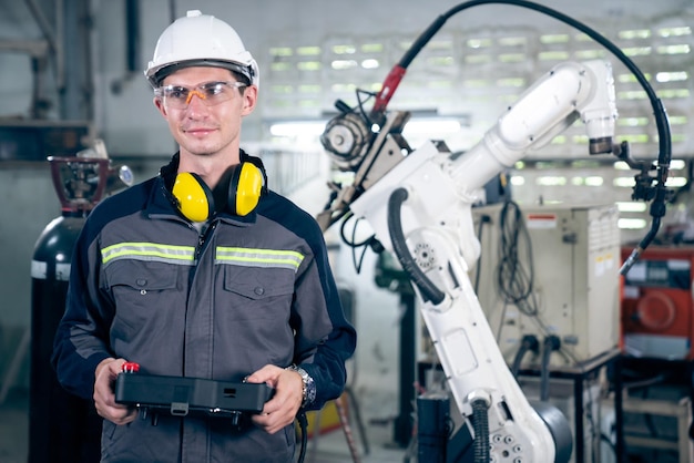 Young factory worker working with adept robotic arm