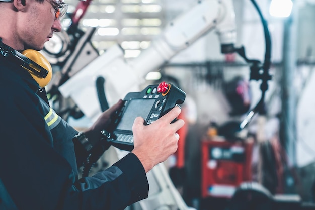 Young factory worker working with adept robotic arm