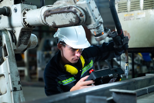 Young factory worker working with adept robotic arm