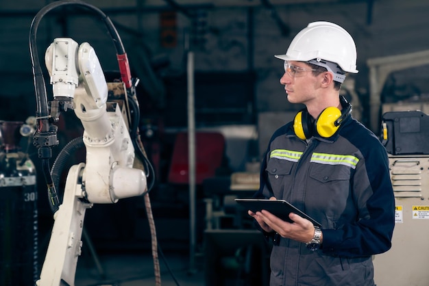 Foto giovane operaio di fabbrica che lavora con un abile braccio robotico