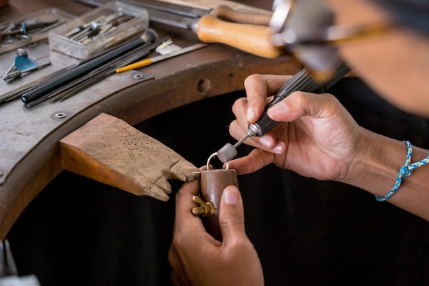 Young faemale jeweler polishing jewelry in workshop