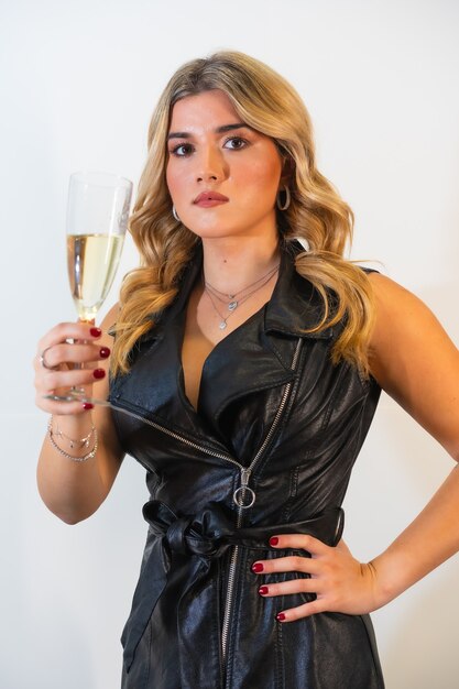 Young fairhaired lady in a black stylish dress posing with a glass of champaign