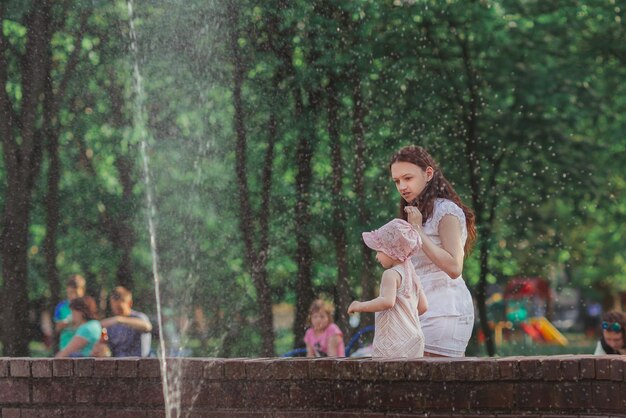 Young families with children resting near the fountain on a hot summer day