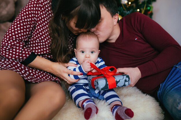 新年のツリーの近くでクリスマスを祝う若い家族小さな子供のためのプレゼントすべてが陽気です