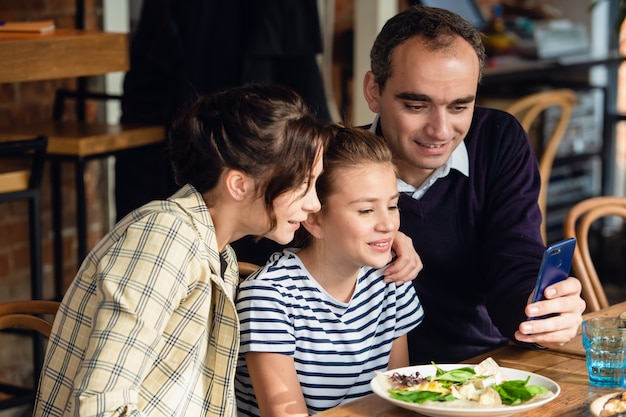 Photo young family chatting on the phone at the dinner table