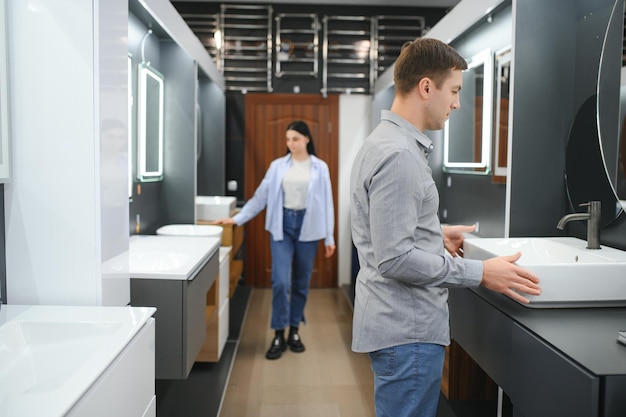 Photo young family couple choosing bathroom sink in bathroom fixtures store