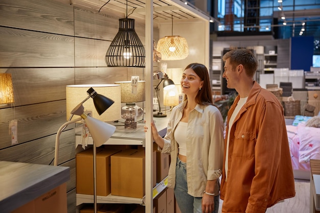 Young family couple choosing chandelier in building shop center