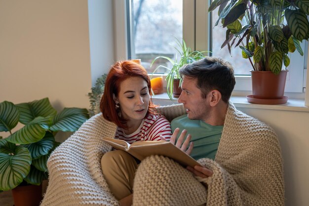 Young family couple man and woman discussing new book while reading together at home