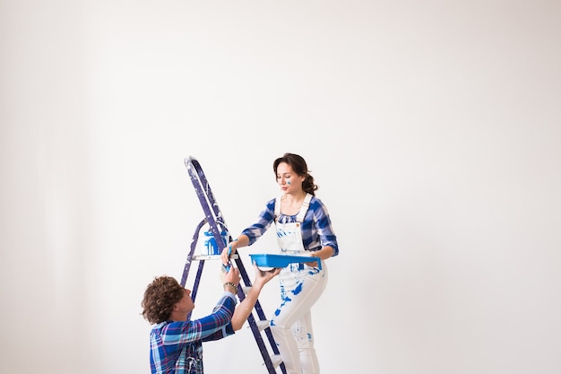 Young family doing repair, painting walls together and laughing.