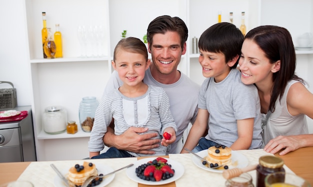 Young family eating fruits and pancakes for breakfast 