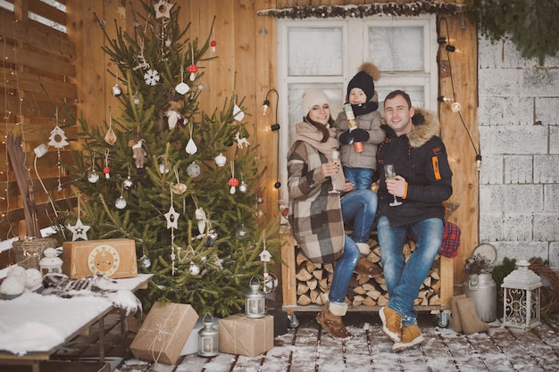 Young family enjoying their holiday time together, decorating Christmas tree outdoors 