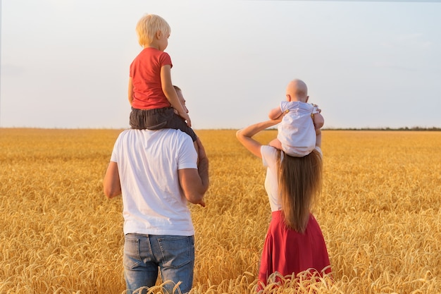 Молодая семья в поле с двумя маленькими детьми