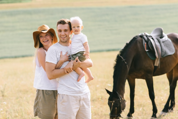 Молодая семья весело провести время в поле. Родители и ребенок с лошадью