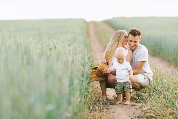 A young family have fun with their little baby in the field