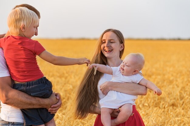 Young family having fun ourdoors. Mom dad and two kids in wheat field. Lifestyle.