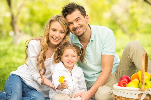 Young family having picnic outdoors.