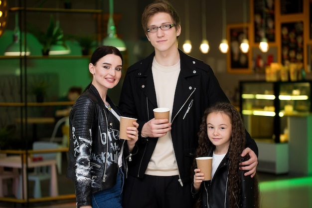 Young family having time in a cafe after shopping Mom dad little daughter drink tea and cafe