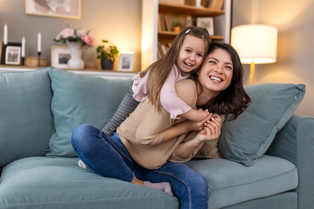 Young family hug and portrait of child with mother mom or mama bond relax and enjoy quality time together Love happy family and woman with kid girl smile care or lounge on home living room sofa