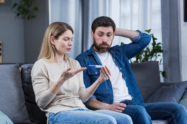 Young family man and woman are not satisfied and disappointed with the result of the pregnancy test