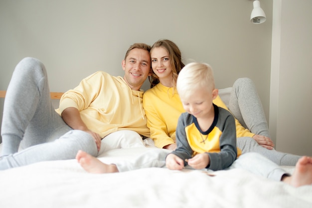 Young family mom and dad play with son in bed