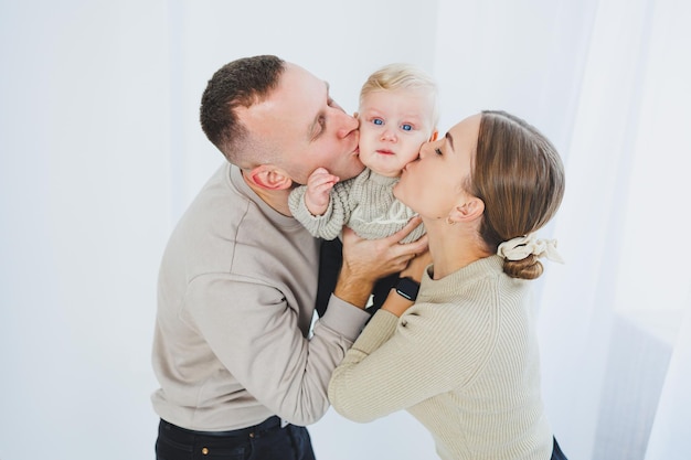 幼い家族6ヶ月の息子と一緒に白い背景で結婚した夫婦が小さな息子を抱きしめる家族関係