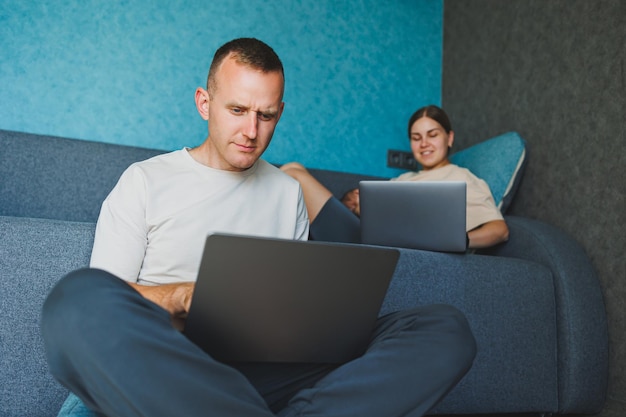젊은 가족, 어머니, 아버지와 딸이 거실에서 함께 시간을 보내고, 아파트에서 휴식을 취하는 가족의 라이프 스타일, 남자가 노트북과 여성과 태블릿을 가지고 일하는 동안.