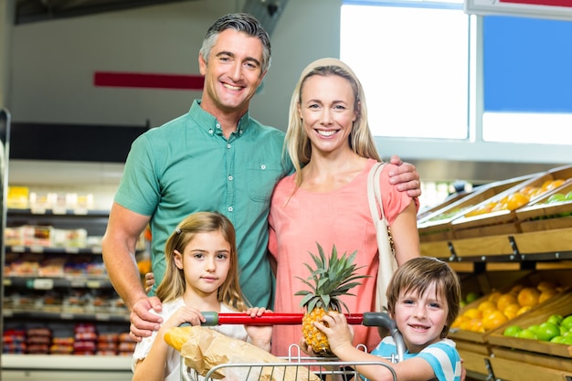 Foto giovane famiglia che propone insieme al carrello