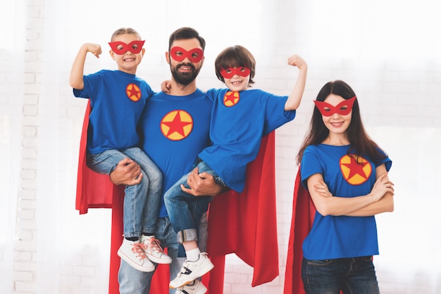 Young family in red and blue suits of superheroes.