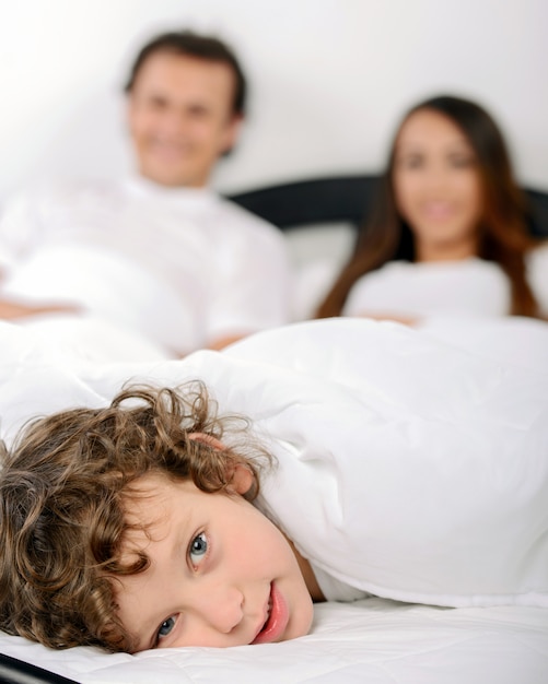 Young family resting together in parents bed.