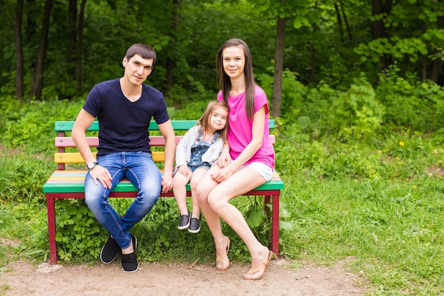 Young family sitting on a bench in the summer park.