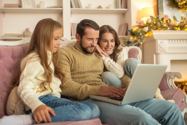 Giovane famiglia seduta guardando eccitato mentre si dispone di una videochiamata