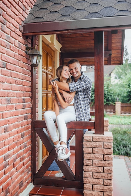 Photo young family standing at the porch of the house and hugging.