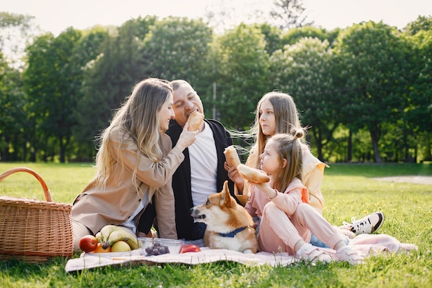 Young family and their corgi dog having picnic in a park